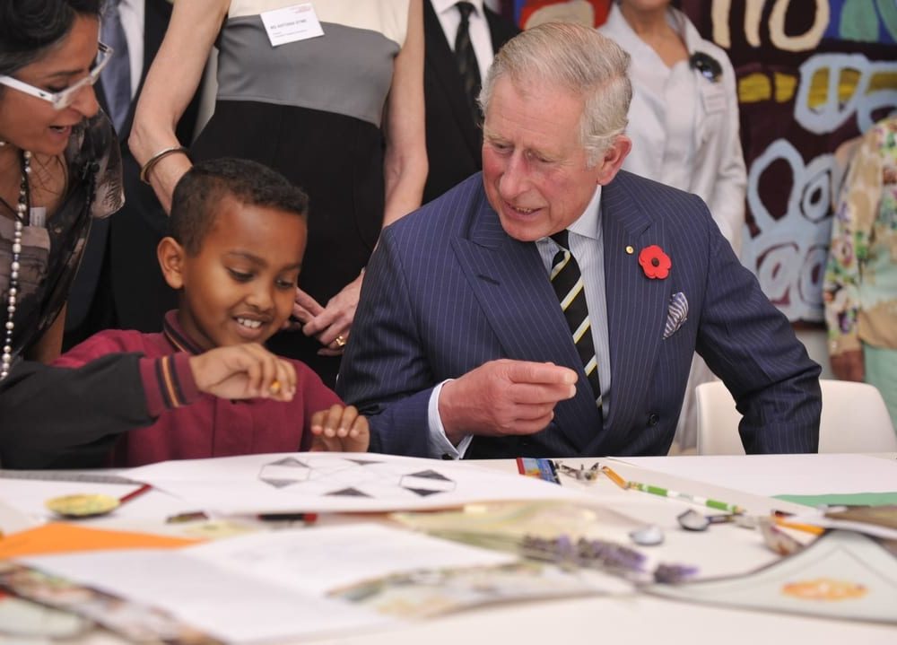 King Charles III with a young child at a table
